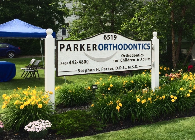 Parker Orthodontics outdoor business sign with flowers and landscaping in front yard setting.
