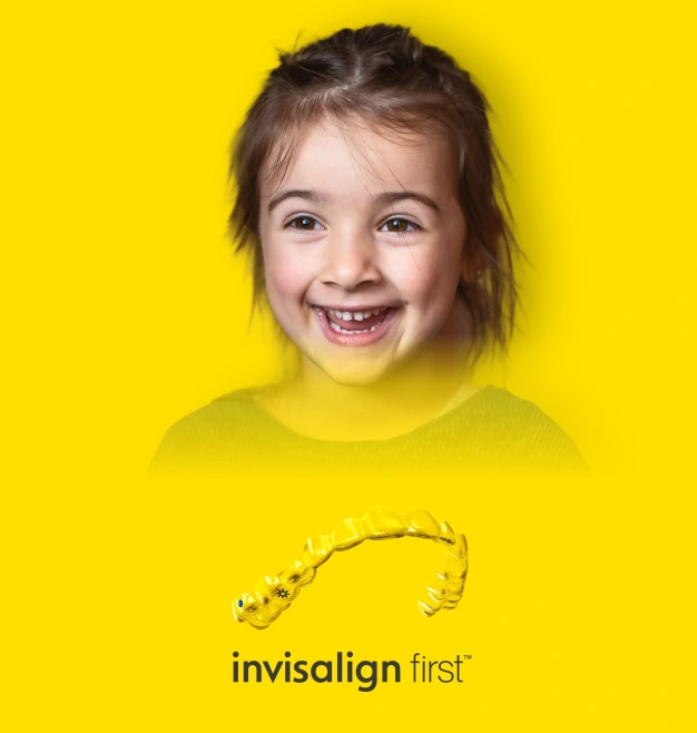 Young girl smiling brightly against yellow background wearing yellow shirt with Invisalign First logo.