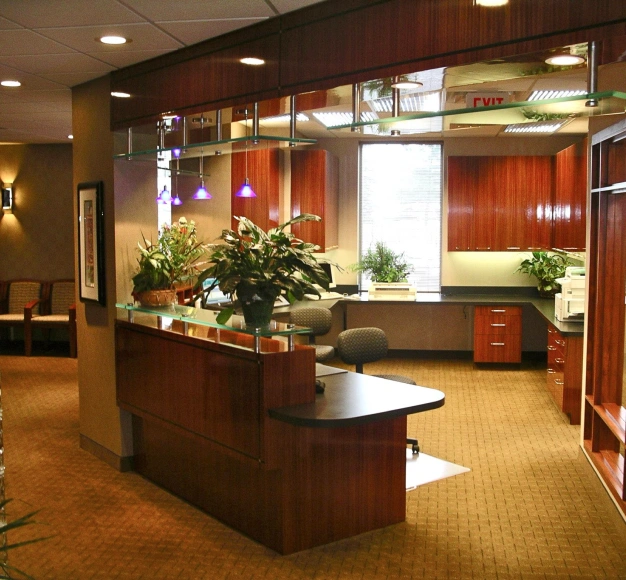 Modern dental reception area with wooden desk, plants, and warm lighting in professional office.
