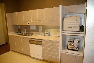 Vintage orthodontic office kitchenette with beige cabinets, appliances, and storage units.