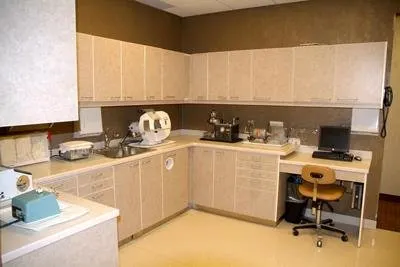 Modern orthodontic office break room with light wood cabinetry, appliances, and workspace furniture.