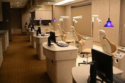 Modern orthodontic treatment rooms with dental chairs, equipment, and purple pendant lighting in clinical setting.