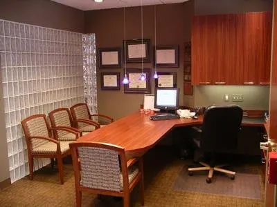 Modern orthodontic office reception area with wooden desk, waiting chairs, and professional décor.