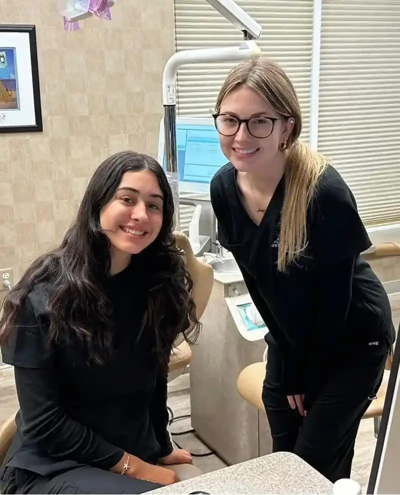 Two dental team members smiling together in a treatment room at the practice.