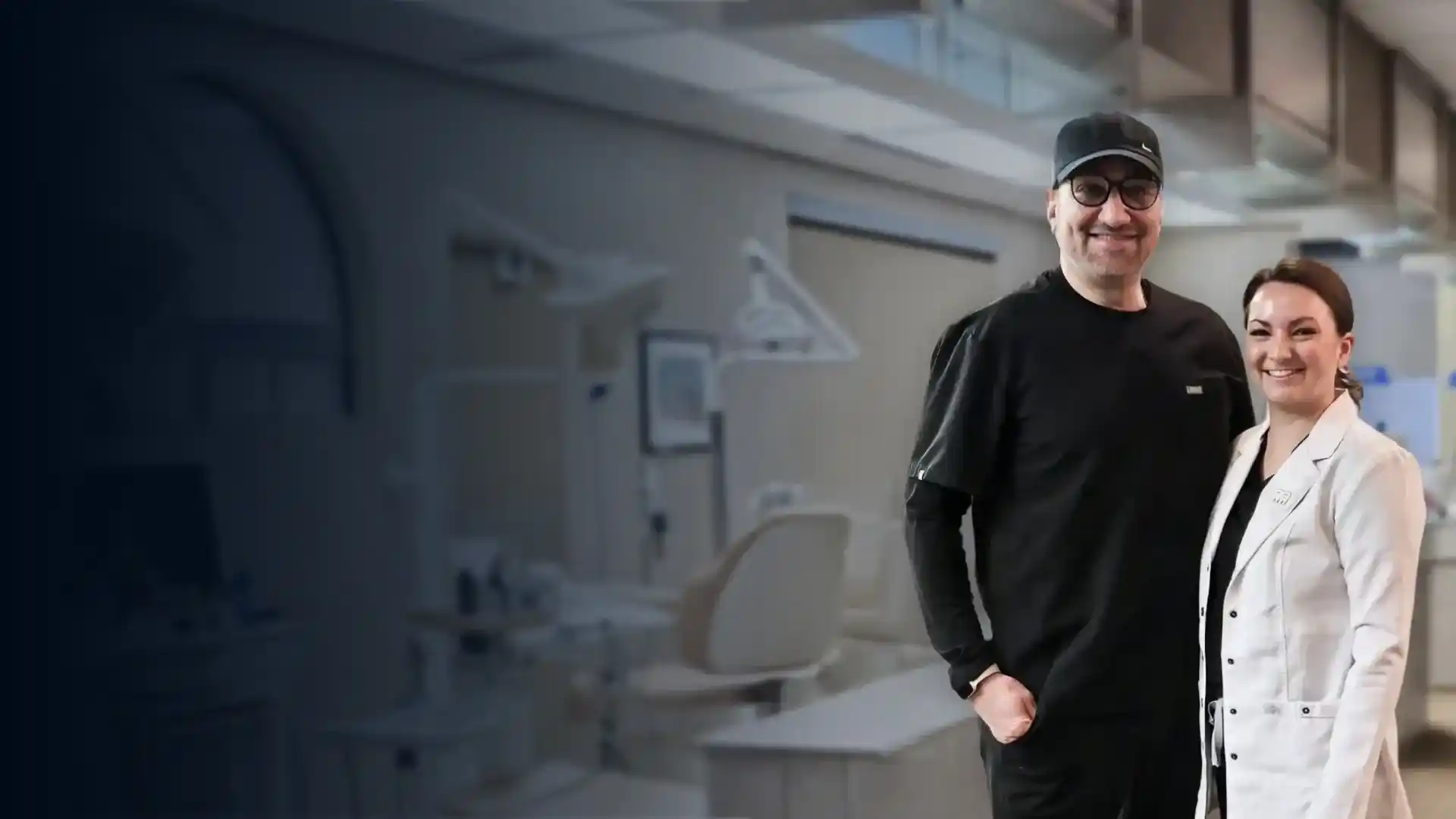 Two people stand in a modern orthodontic office with blue-tinted glass walls and medical equipment visible in background.